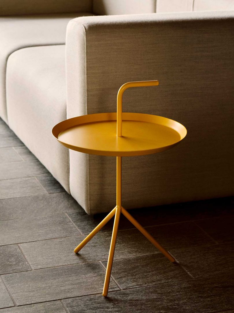 Small metal end table in yellow next to beige sofa