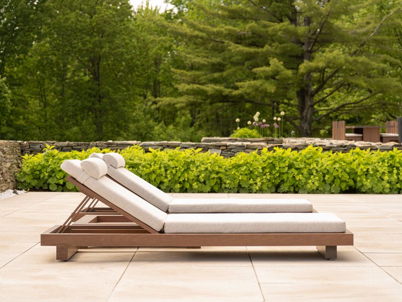 outdoor chaise lounge in wood with neutral upholstery sitting outdoors