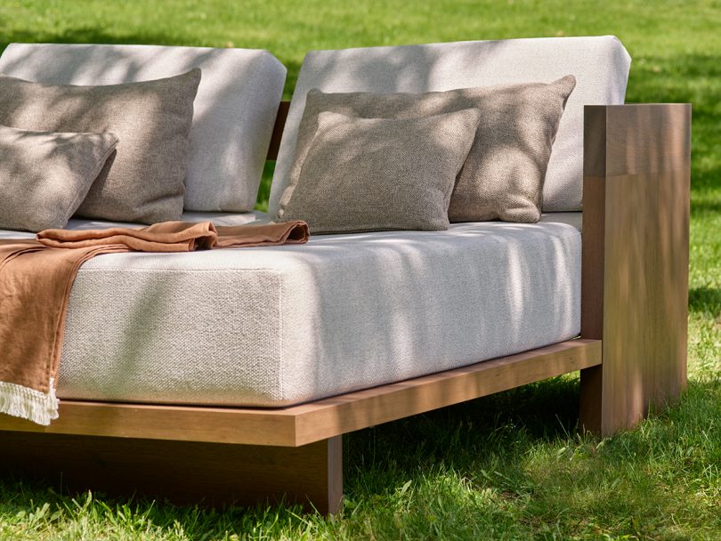 outdoor daybed in wood with neutral upholstery sitting outdoors