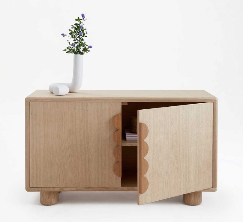 light wood sideboard with vase of flowers on white background