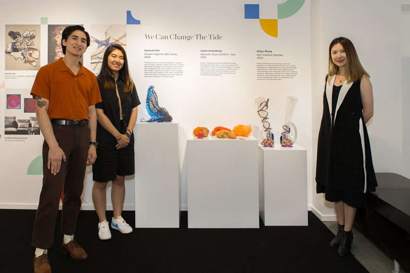 three people standing in front of their designs that are displayed on white plinths