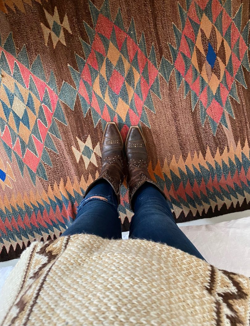 looking down and cowboy boot clad feet on a geometric rug