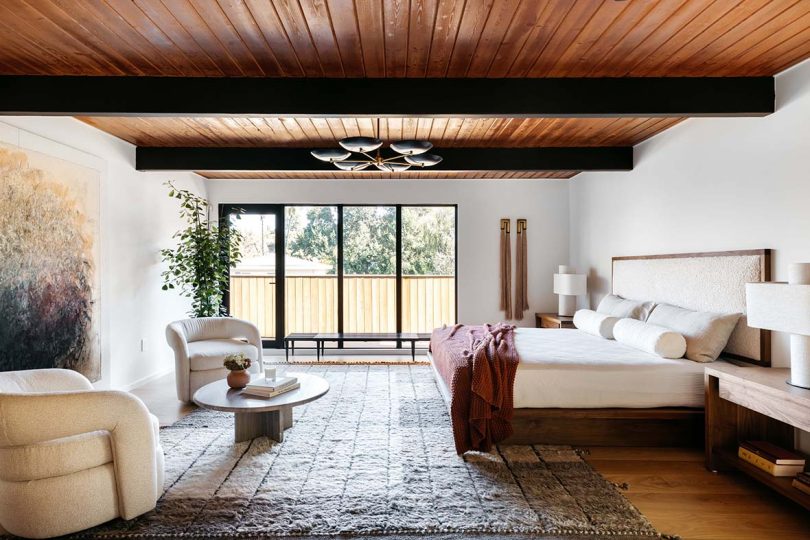large neutral bedroom with large windows and wood ceiling
