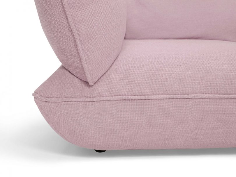corner of a light pink upholstered furniture on white background