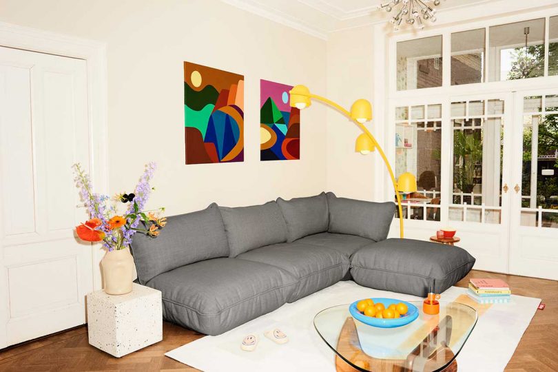 modern living space with dark grey L-shaped sofa and arched yellow floor lamp