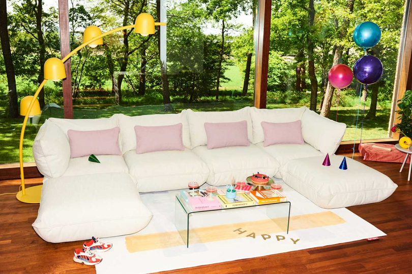 modern living space with white modular sofa with pink pillows and arched yellow floor lamp