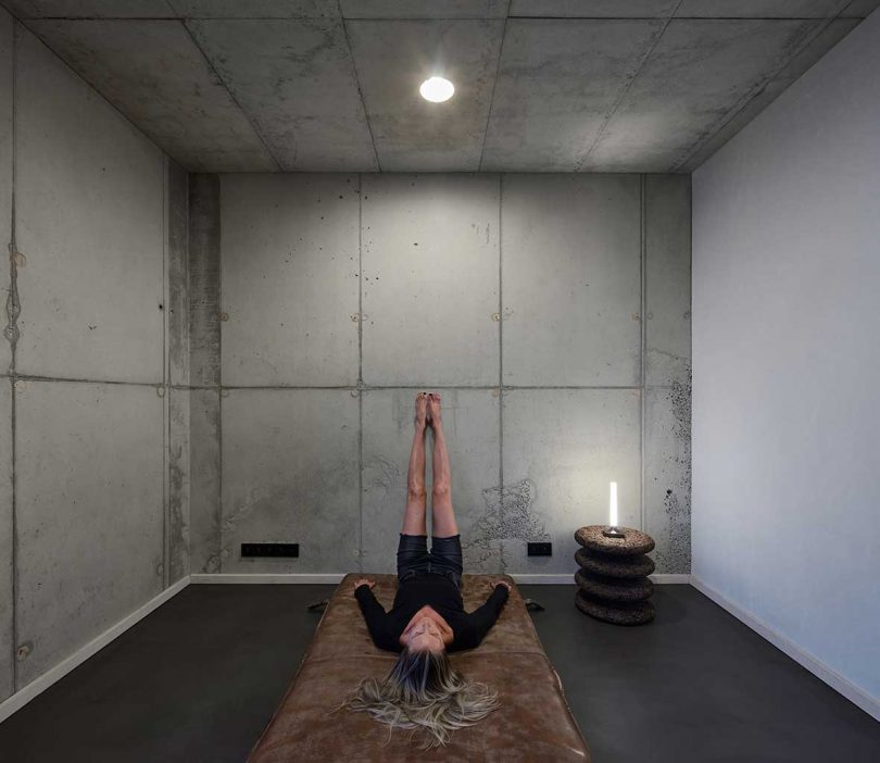 interior room with concrete walls and ceiling and person with legs up the wall