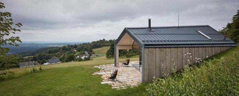 angled side view of wood and dark steel house on green land