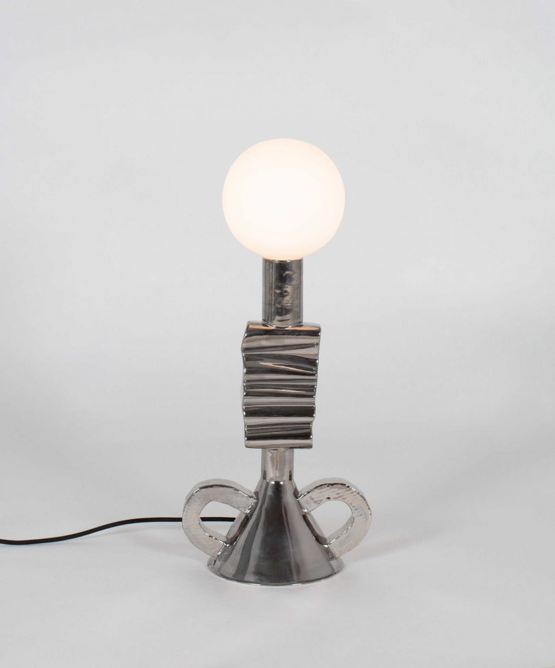 dark grey shade-free table lamp on a light grey background
