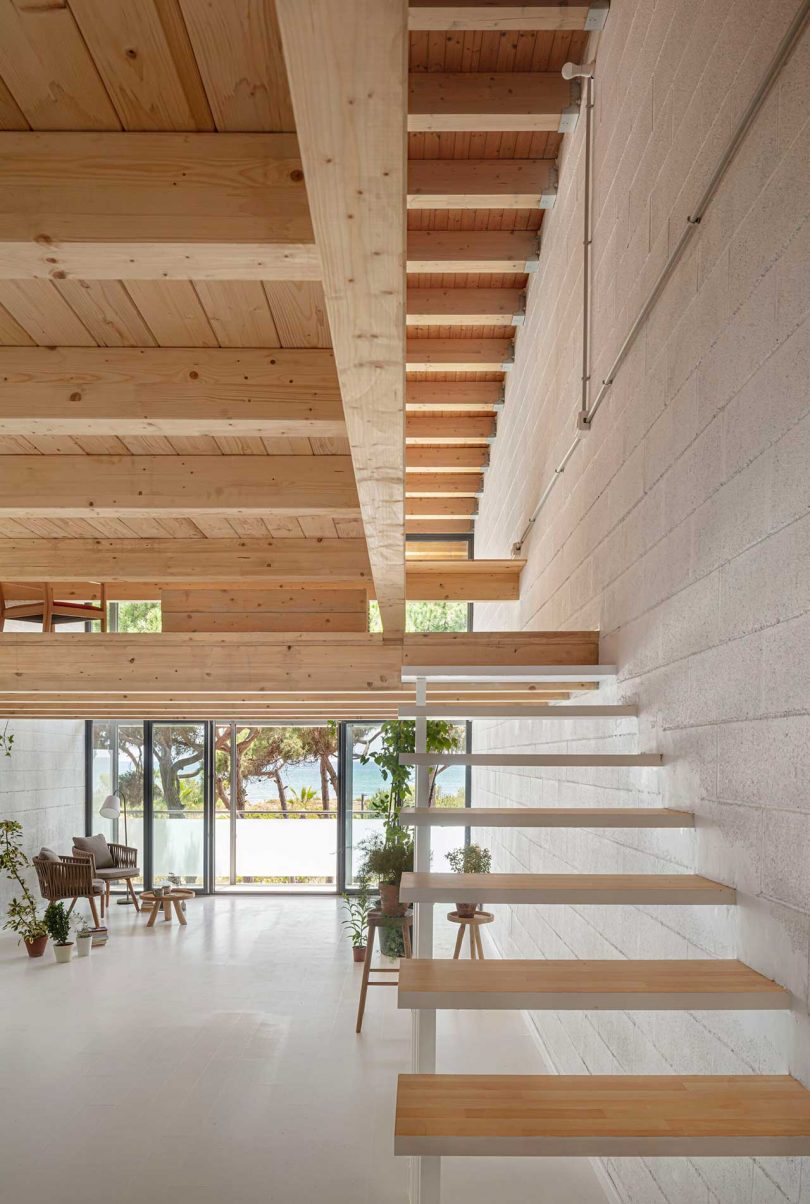 minimalist house interior with white surfaces and wood details looking out through front windows