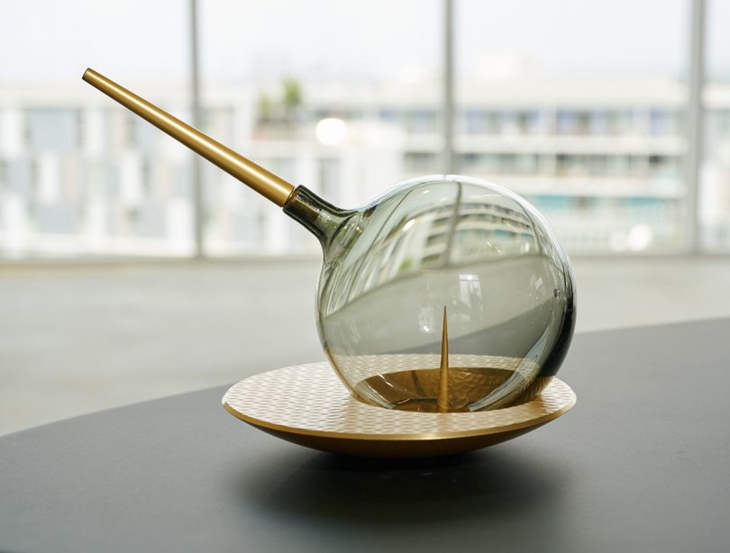 The Globe, a hand blown glass sphere with brass stem displayed on table.
