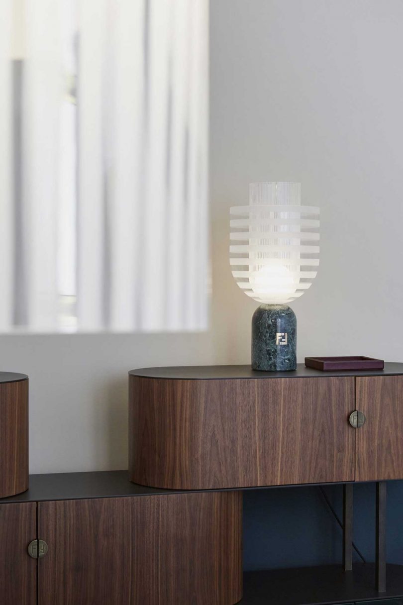 glass table lamp sitting on a credenza in a styled living space