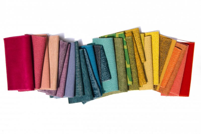 تخت منحنی از نمونه های پارچه ای تا شده در رنگین کمان رنگ