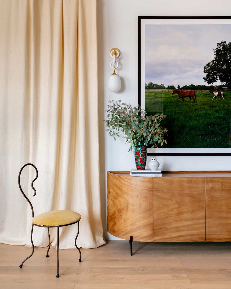 styled living space with wood credenza, dining chair, wall art, and suspended wall sconce