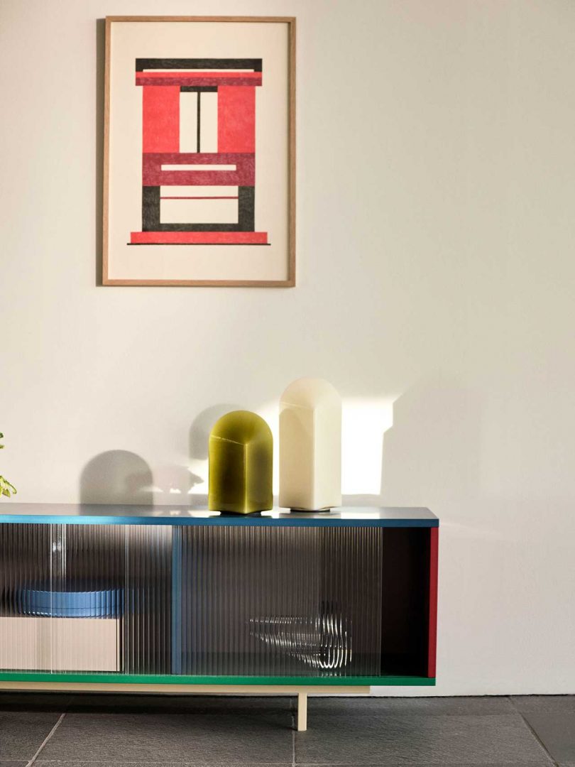 one green and one white table lamp of varying heights on a console