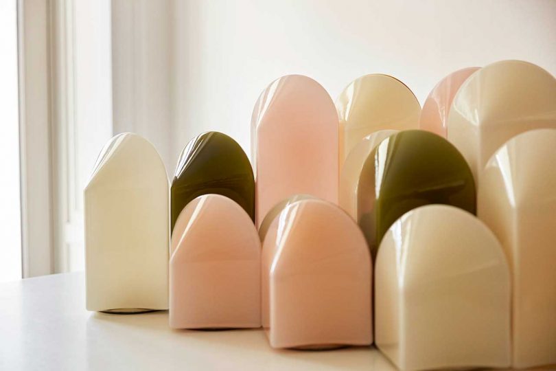 group of white, green, and pink table lamps of various heights grouped together