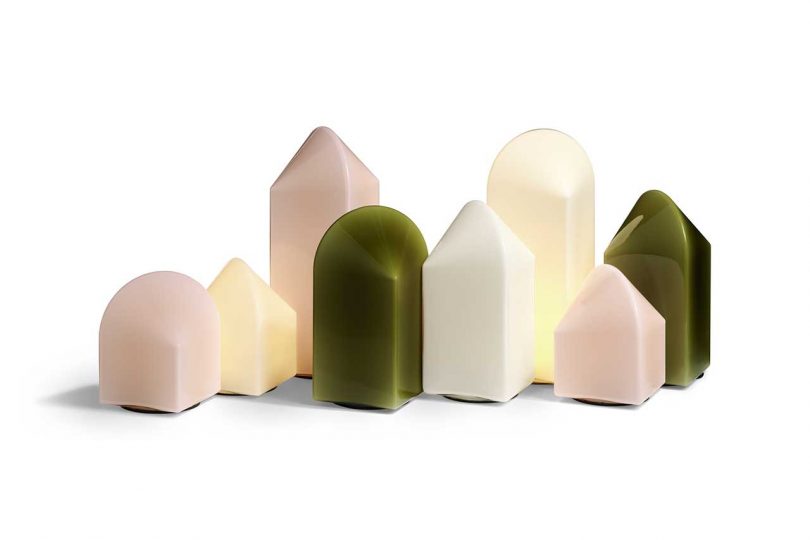 group of lit white, green, and pink table lamps of various heights grouped together on a white background