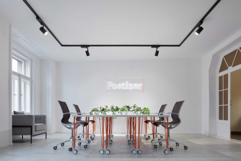 office interior facing large white conference table with black chairs