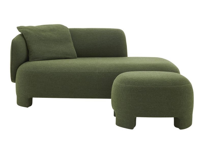 dark green upholstered lounge chair with pillow and ottoman on white background