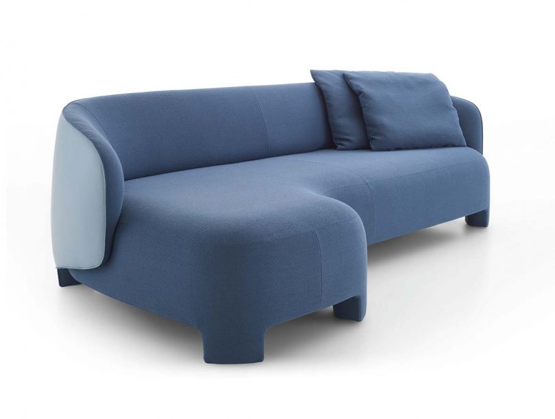 blue upholstered lounge sofa with pillows on white background