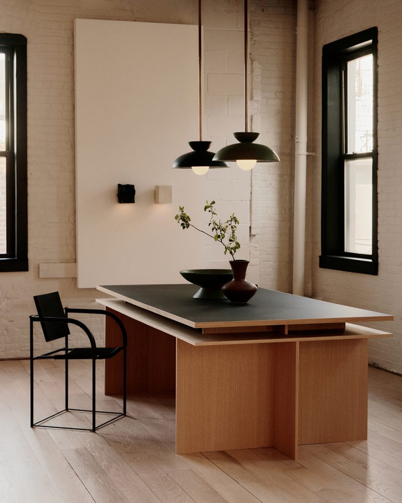 two dark pendant lamps hanging above a desk