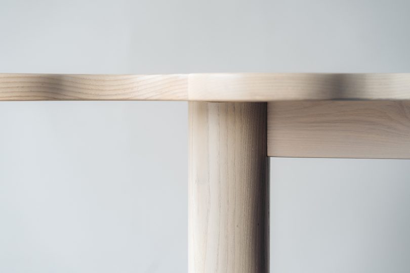 detail of light wood diamond-shaped dining table with six legs and a wavy edge