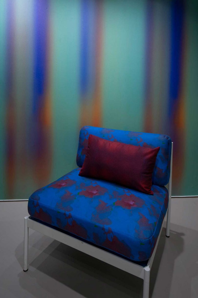 blue floral print chair in front of colorful gradient wall