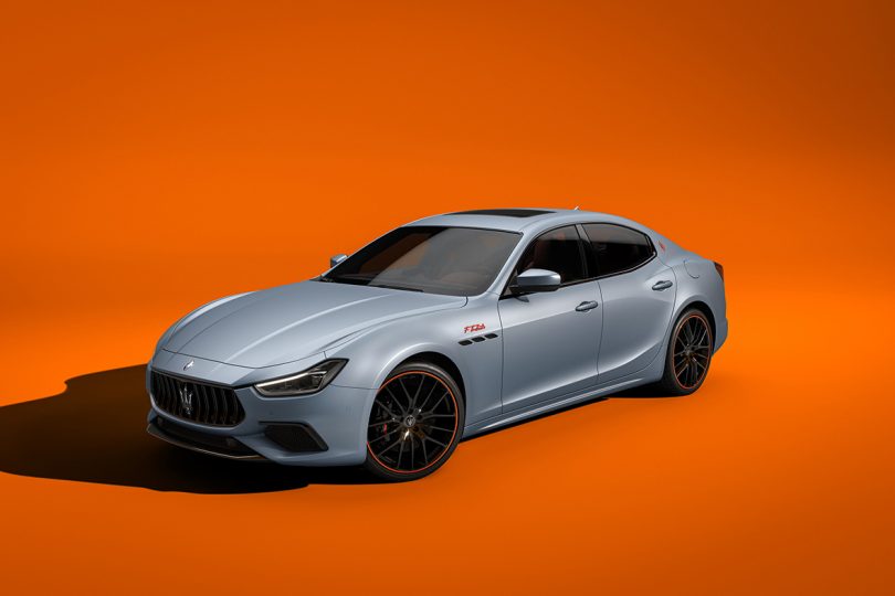 Front angle view of Maserati Ghibli F Tributo Special Edition is also available in grey colored Grigio Lamiera against deep orange background.