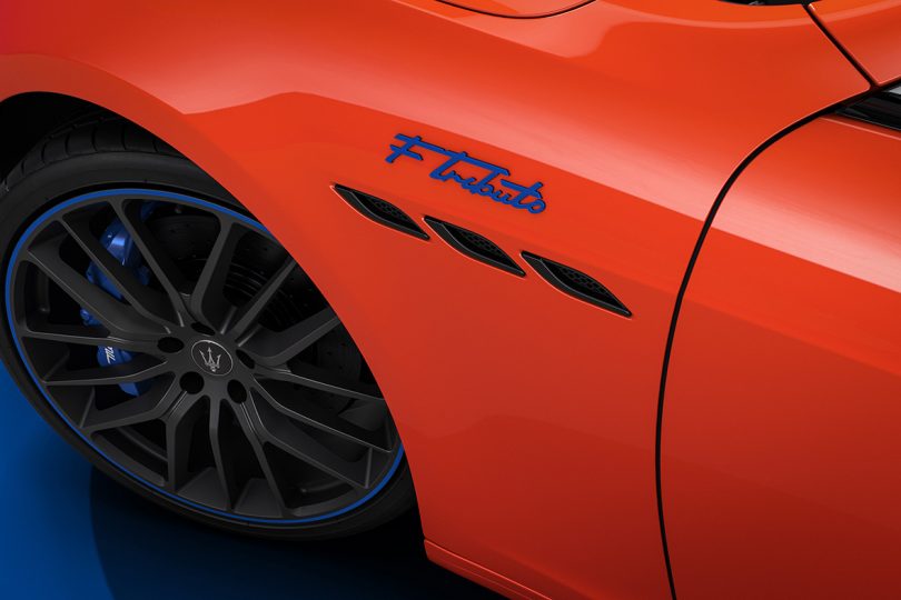 Detail of Maserati F Tribute emblem in blue against orange body paint over front wheel well.