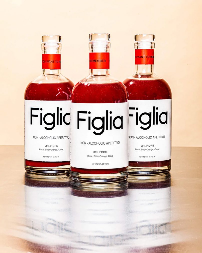 three bottles filled with red liquid, their labels read Figlia