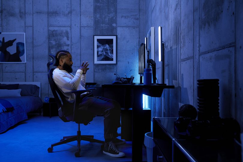 modern living space lit by neon light with man sitting at desk for gaming