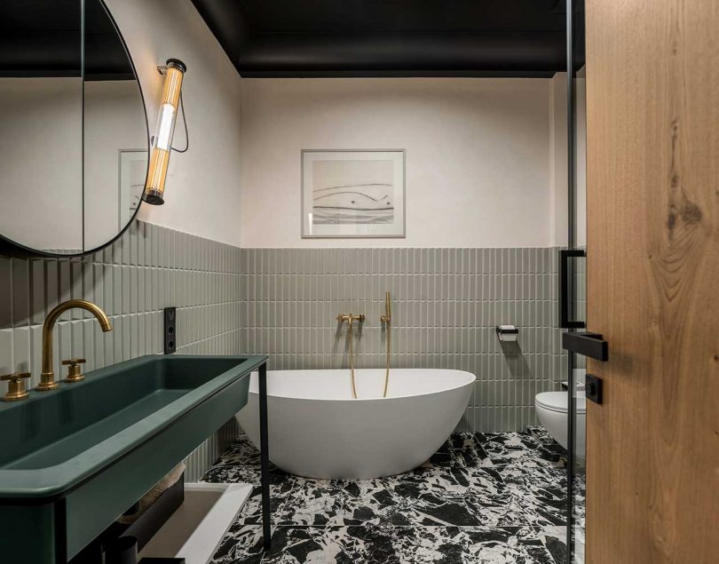 modern bathroom with sage green tiles and a standing green sink and bathtub