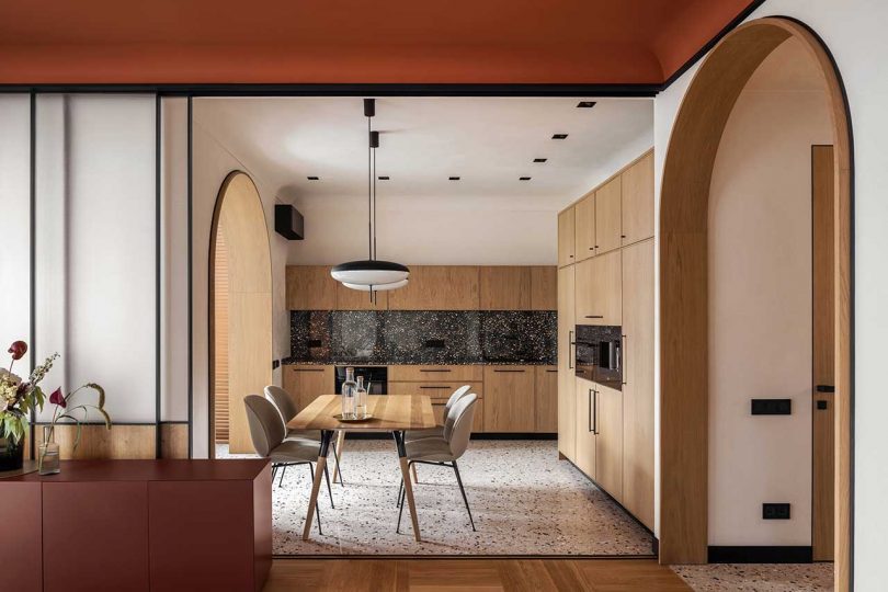 view of modern apartment interior of kitchen with light wood cabinets and terrazzo floors