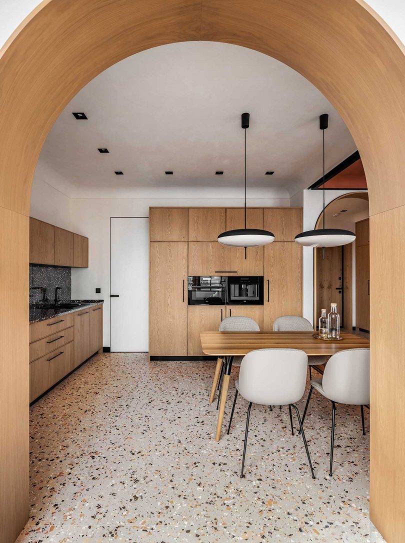 view of modern apartment interior of kitchen with light wood cabinets and terrazzo floors