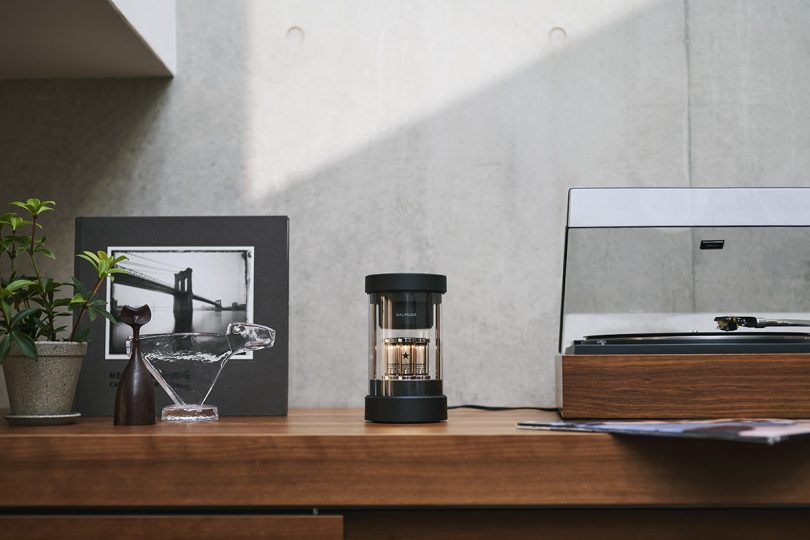 BALMUDA black speaker sitting on shelf next to turntable