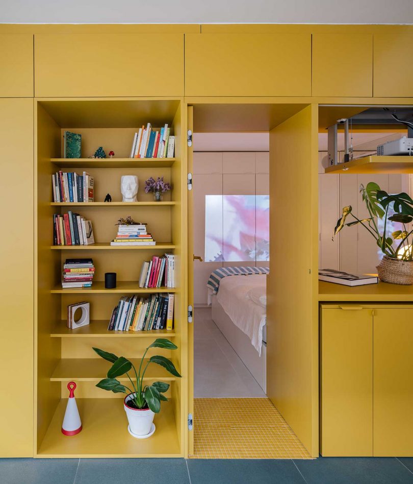 interior apartment view of yellow built-in shelves with passageway to small bedroom