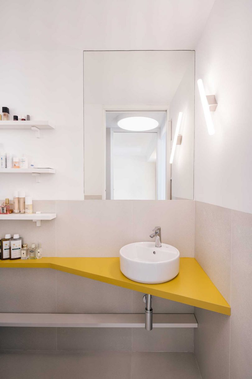 نمای حمام کوچک با پیشخوان زرد گوشه و سینک کوچک سفید