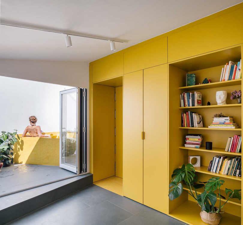 modern apartment interior with bold yellow storage and large windows with views to deck