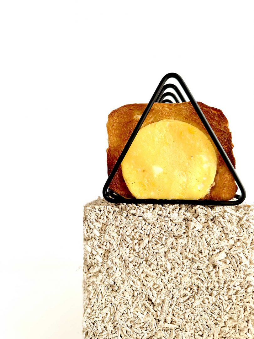 Food display with block and triangular wire shelf with toast with egg in center