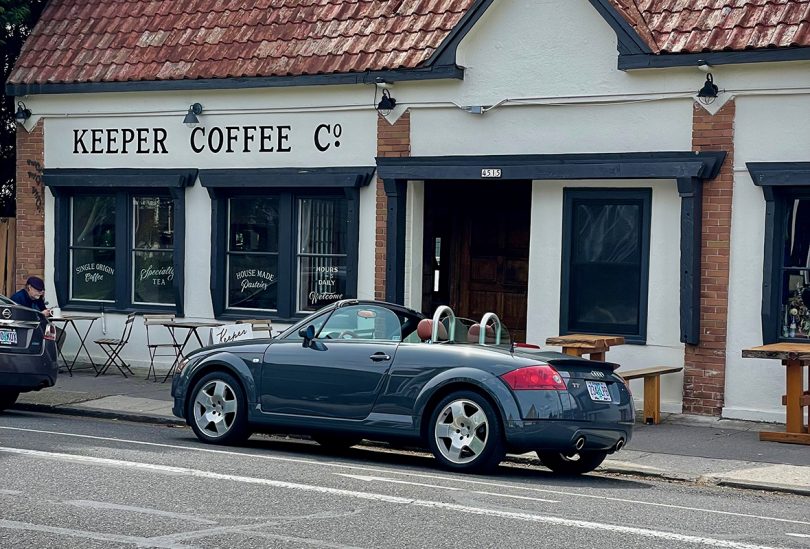 sports convertible parked in front of a coffee shop
