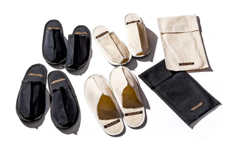 down view of multiple pairs of waxed canvas slippers and their cases in black and natural