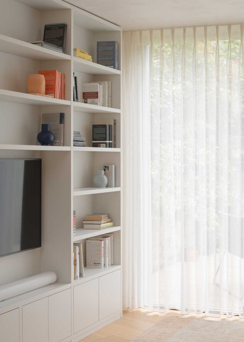 closeup shot of modern white bookcase and sliding glass doors with curtains