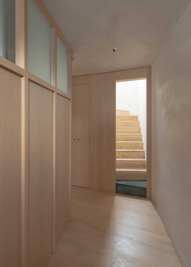 interior view down light wood clad hallway leading to staircase