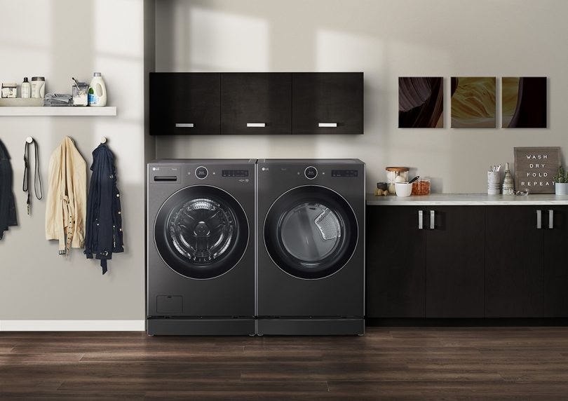 black front load washer and dryer pair in a space with cream colored walls and dark cabinetry