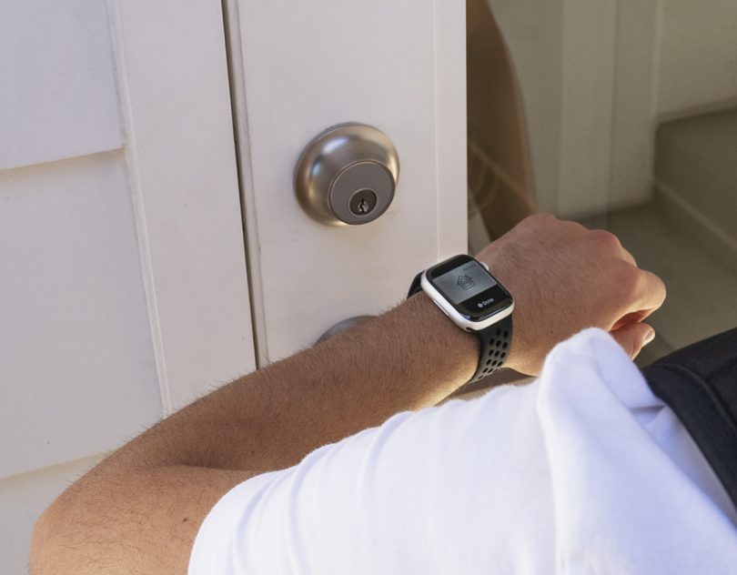 Man in white t-shirt and wearing an Apple Watch unlocking Level Lock+ by proximity.