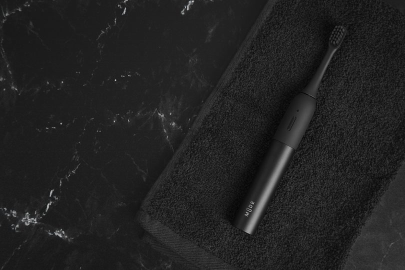 minimalist black electric toothbrush on black towel