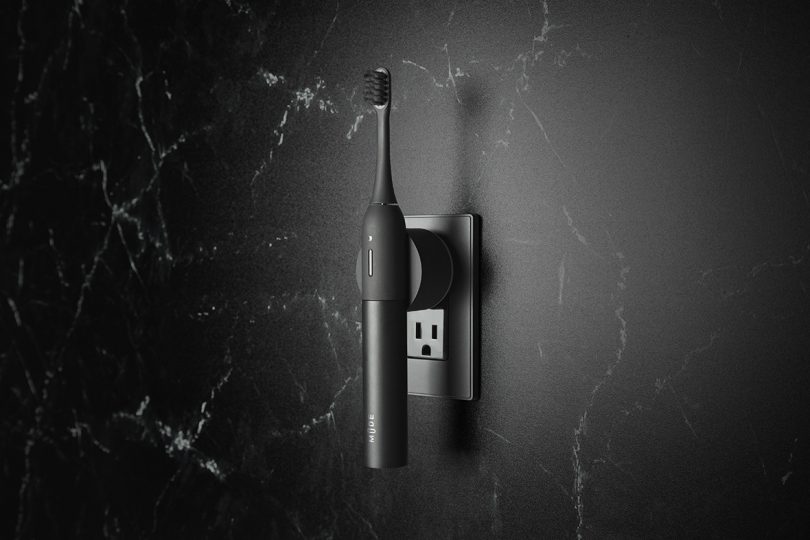 minimalist black electric toothbrush mounted to adapter plugged into wall socket