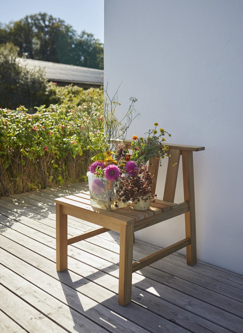 modern wood outdoor dining chair with a vase of flowers