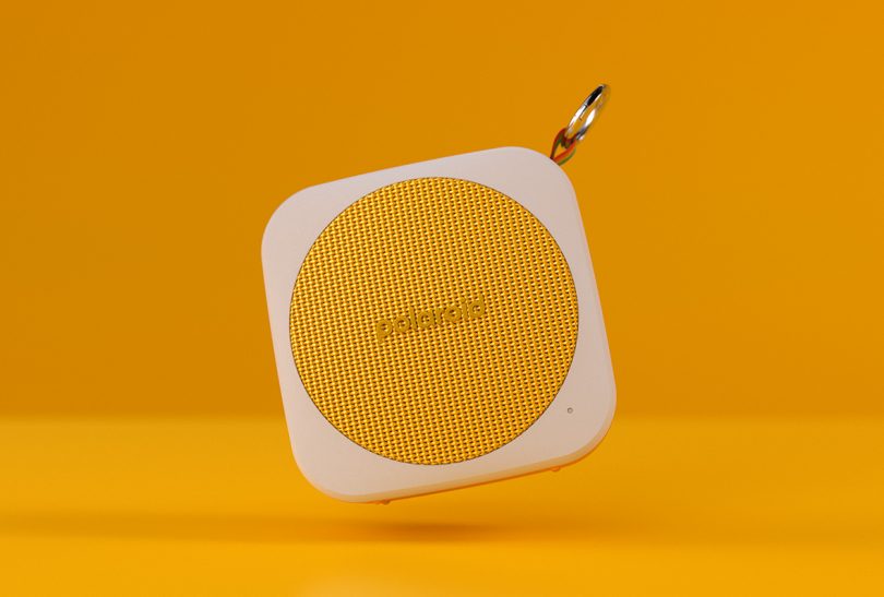 yellow backdrop with yellow and white Polaroid P1 speaker in front