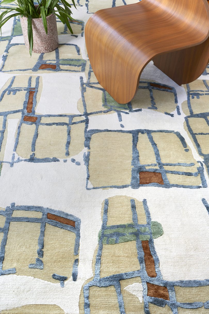styled floor carpet with an abstract pattern in beige, rust, and blue